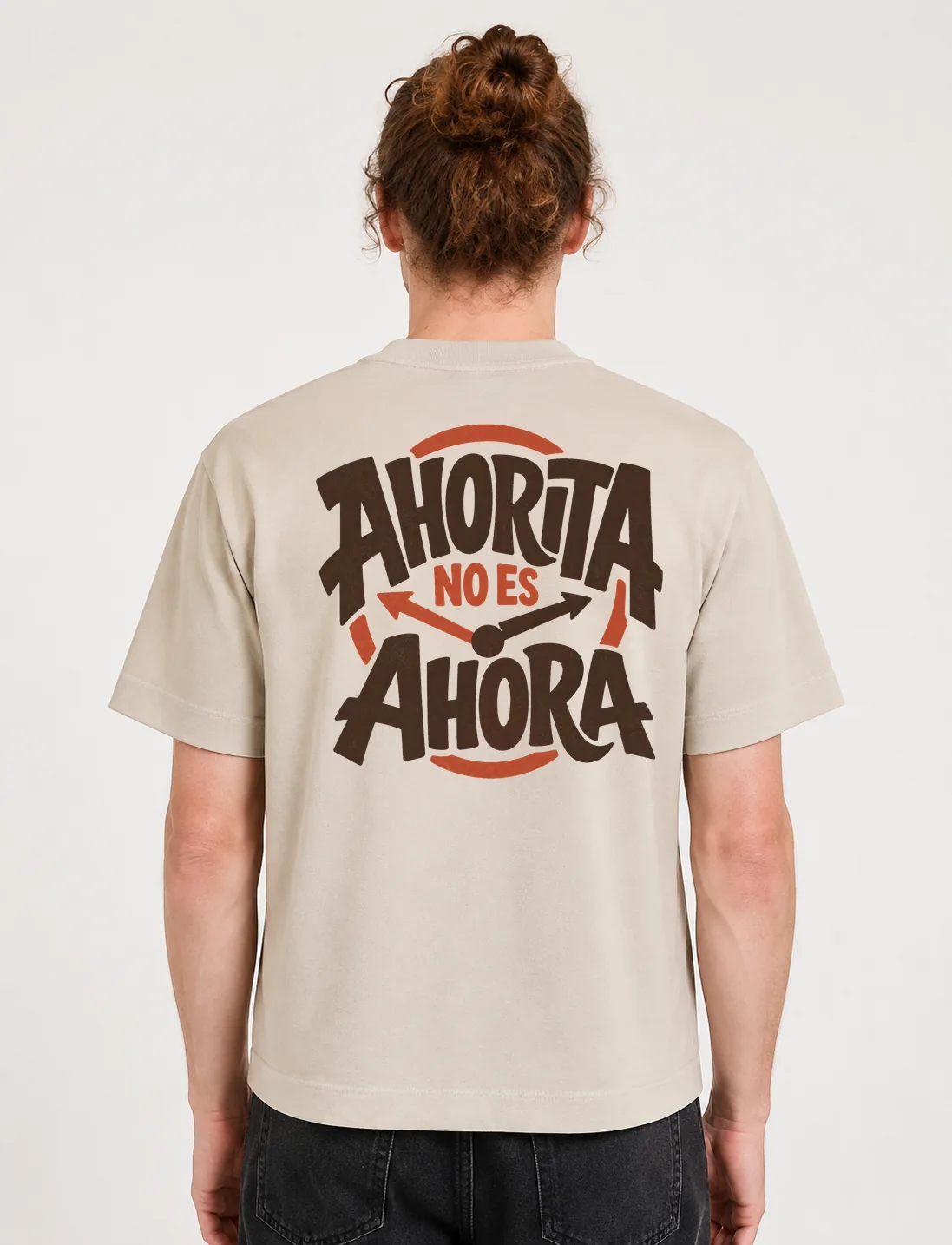 Espalda de una camiseta Cream oversized con el diseño «Ahorita No Es Ahora»: manecillas y flechas de reloj cruzando las palabras