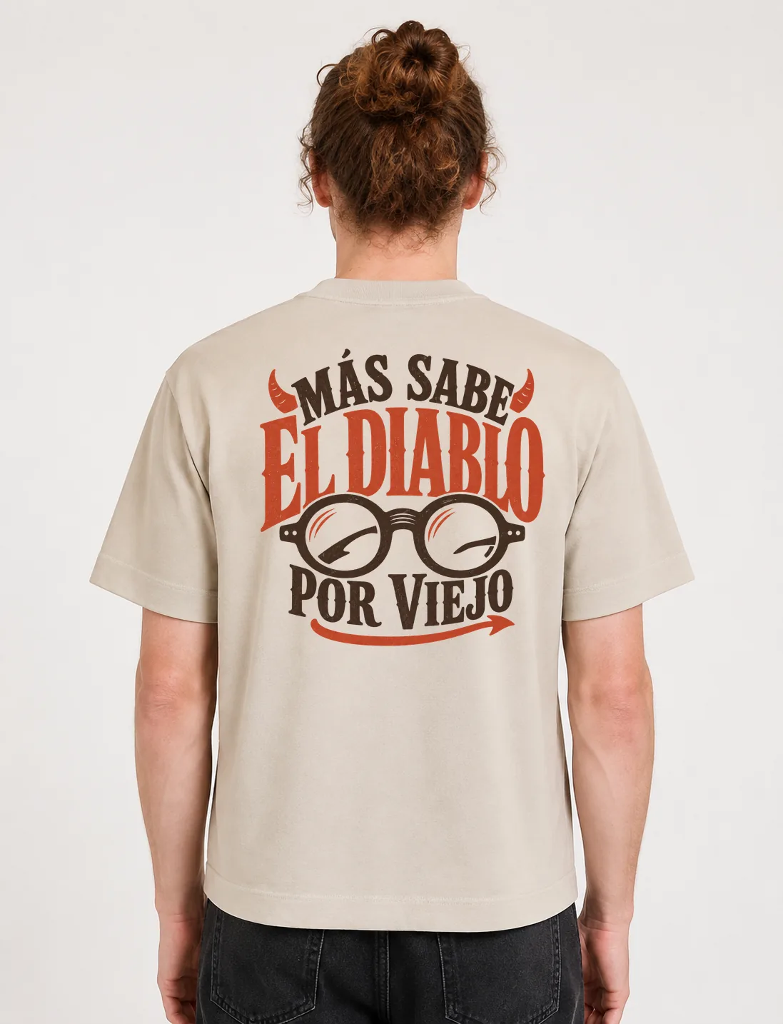 Espalda de una camiseta Cream oversized con el diseño «Más Sabe el Diablo por Viejo»: unos lentes redondos y un par de cuernitos sobre las letras
